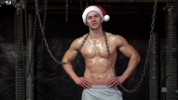 Young shirtless muscular man standing among metal chains, looking at camera — Stock Video