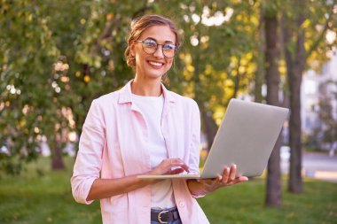 İş kadını yaz parkında dizüstü bilgisayarla uzaktan kumandayla çalışıyor. Açık havada başarılı Avrupalı Kafkasyalı serbest çalışan kadın video çağrı öğretmenini çevrimiçi derslere çalıştırdı 