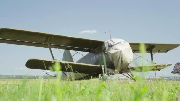 Старый советский военный самолет Антонов Ан-2 приземлился на фоне травянистого голубого неба — стоковое видео