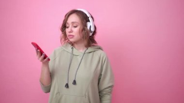 Mutlu dişler gülümser kadın pembe arka planda müzik kulaklıkları dinler.