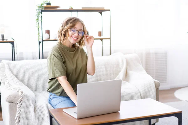 Gözlüklü Bir Kadın Dizüstü Bilgisayar Kullanıyor Klavye Kullanıyor Kanepeye Oturuyor — Stok fotoğraf