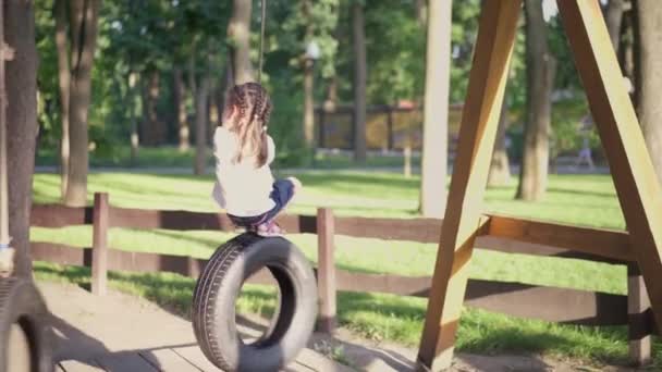 Little Girl Swinging Swing Tire Outdoor Public Park Day Summer Happy Childhood — Stock Video