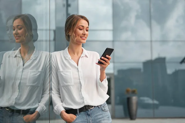 Businesswoman successful woman business person standing outdoor corporate building exterior cell phone Pensive elegance cute caucasian professional business woman middle age dreaming with mobile phone