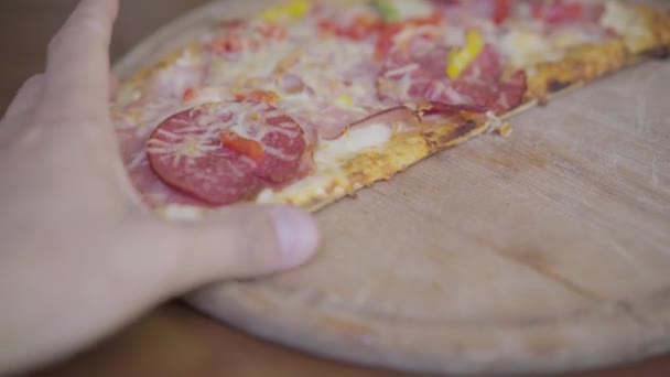 피자 슬라이스를 손으로 잡는 사람 목판을 클로즈업 — 비디오