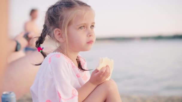 Hungrige kleine Mädchen essen Sandwich am Strand sitzen Sommertag — Stockvideo