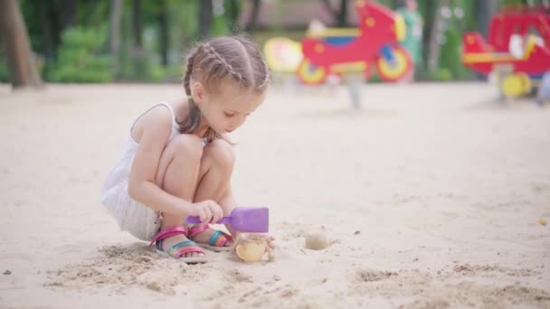 Holčička hraje pískoviště hřiště kopání písek Shovel budova písek postava letní den — Stock video