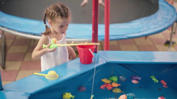 Niño pescador captura de plástico juguete pescado en la piscina Parque de atracciones Día de verano — Vídeos de Stock