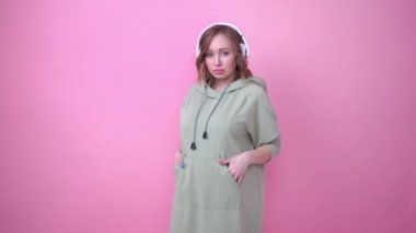 Mutlu dişler gülümser kadın pembe arka planda müzik kulaklıkları dinler.
