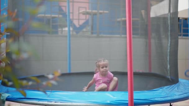 Bambina salto trampolino attrezzature cortile divertirsi estate calda giorno caucasico Femmina bambino godere della vita tempo libero attivo — Video Stock