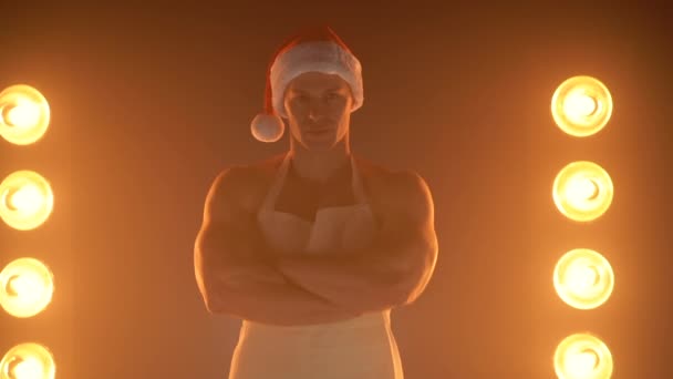 Portrait of muscular chef wearing white apron and chef hat, posing with folded arms on smoky background — Stock Video