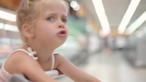 Grappig schattig kind duwen winkelwagen in supermarkt — Stockvideo