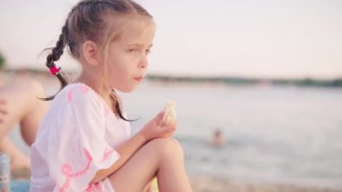 Aç küçük kız yaz tatilinde sandviçini yer. 