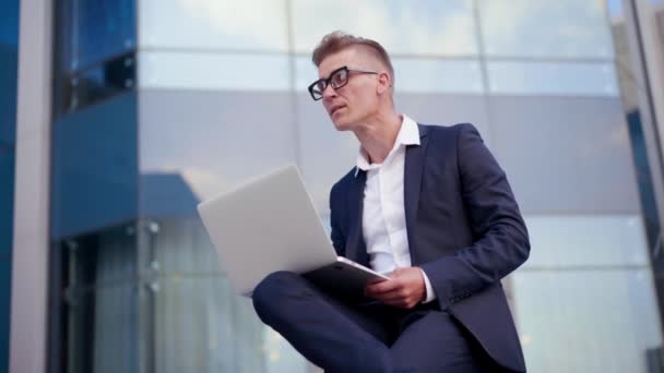 Negócios. Empresário usando laptop sentado ao ar livre — Vídeo de Stock