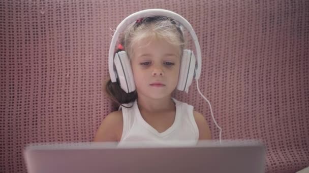 Little Girl Sitting Sofa in Headphones Listen music Use Laptop Have Fun Home Interior Caucasian Female Child Use Technology Modern Children Happy Childhood — Stock Video