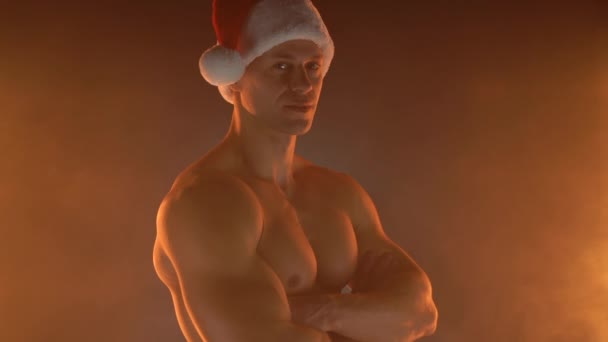 Retrato de homem musculoso usando chapéu de Natal Santa, mãos dobradas sobre fundo fumegante — Vídeo de Stock