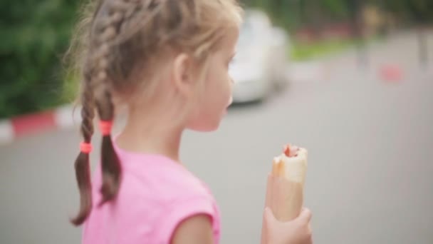 Pequeña niña comer perrito caliente verano parque comida y bebida concepto — Vídeos de Stock