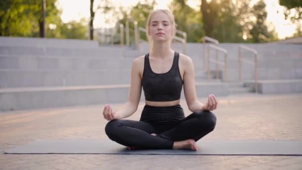 Jóga a meditace v moderním městě Kavkazská žena Relax Lotus Pozice Sedící jóga Mat Venkovní Letní park na betonové podlaze — Stock video