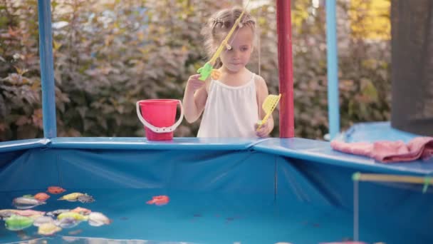 Niño pescador captura de plástico juguete pescado en la piscina Parque de atracciones Día de verano — Vídeo de stock