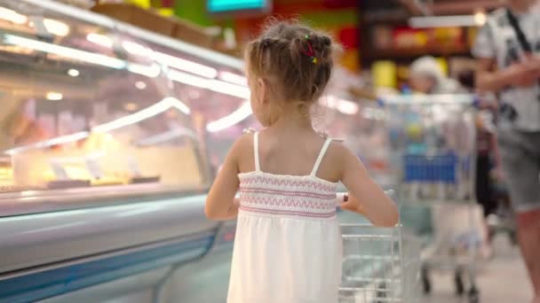 Grappig schattig kind duwen winkelwagen in supermarkt — Stockvideo