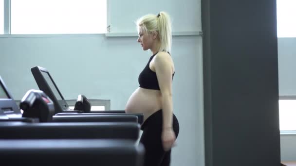 Wanita hamil melatih mesin treadmill di gym Latihan kardio pada simulator berlari — Stok Video