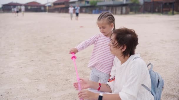 Mutter mit kleinem Kind bläst Seifenblasen am Meer Strand Reisen mit einem Kind Familie Sommerurlaub — Stockvideo