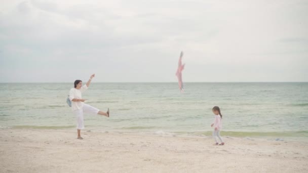 小さな娘が海のビーチでカイトをプレイしている1人の子供を持つ幸せな白人家族は海の海岸で夏休みを楽しんでいます — ストック動画