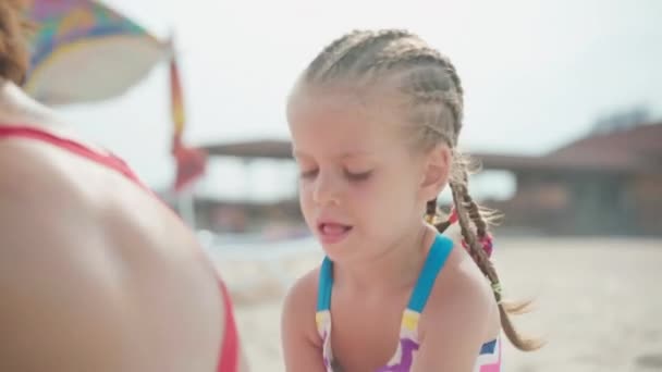 Kleines Mädchen trägt Sonnencreme für Mutter Sommer Meer Strand Familie im Urlaub Kind schützt Mutter vor UV-Strahlung mit Sonnencreme — Stockvideo