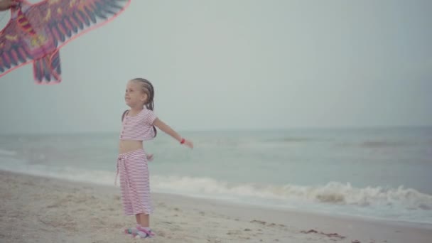 Мать с дочкой, играющая в воздушного змея на морском пляже Счастливая кавказская семья с одним ребенком веселятся на летних каникулах на берегу моря — стоковое видео