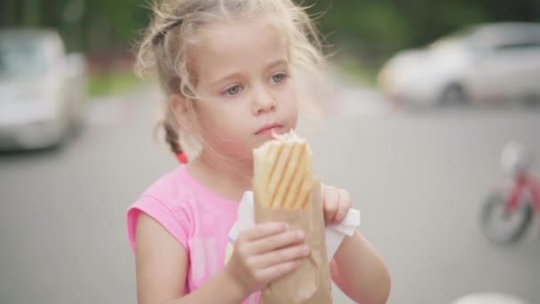 Mała dziewczynka jeść Hot Dog Summer Park Jedzenie i picie Concept — Wideo stockowe