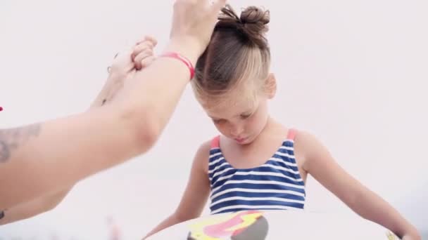 Moeder zorgt voor haar dochters haar bindt haar paardenstaarten — Stockvideo