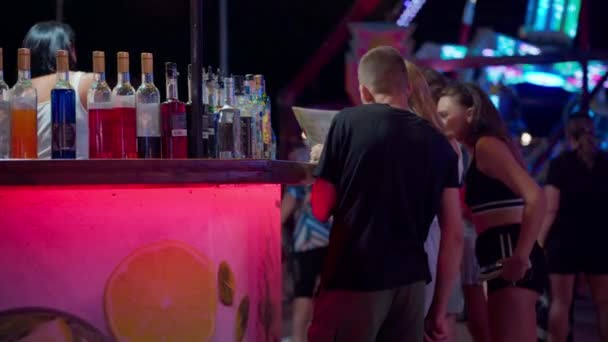 Kirilovka, Oekraïne, augustus 2021 Mensen die alcohol kopen in de buurt van de bar wandelen Pretpark 's nachts — Stockvideo