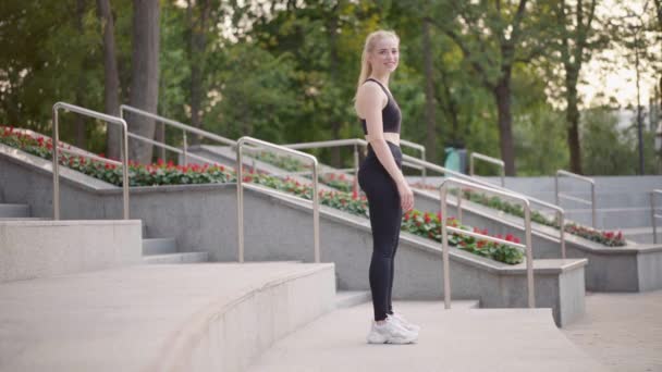 Фитнес Молодая женщина делает загиб упражнения на лестнице стоячие колеса йоги позиции Открытый парк летний солнечный день — стоковое видео