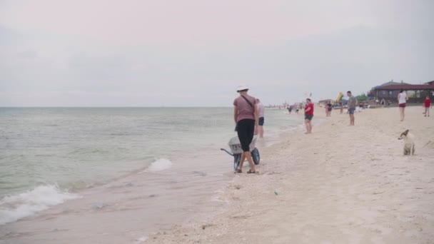 Kirilovka Ucrânia agosto 2021 homem coleta água-viva de praia em um carrinho de mão jovem zelador caucasiano limpa a praia de água-viva — Vídeo de Stock
