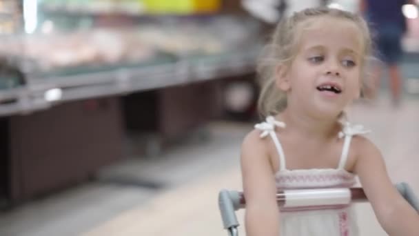 Divertido lindo niño empujando carrito de compras en el supermercado — Vídeos de Stock