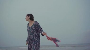 Küçük kızıyla birlikte deniz kıyısında uçurtma oynuyordu. Tek çocuklu mutlu beyaz bir aile deniz kıyısında yaz tatilinde eğleniyordu.