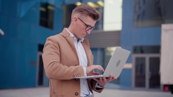 По делам. Бизнесмен с помощью ноутбука на открытом воздухе Взрослый белый мужчина — стоковое видео