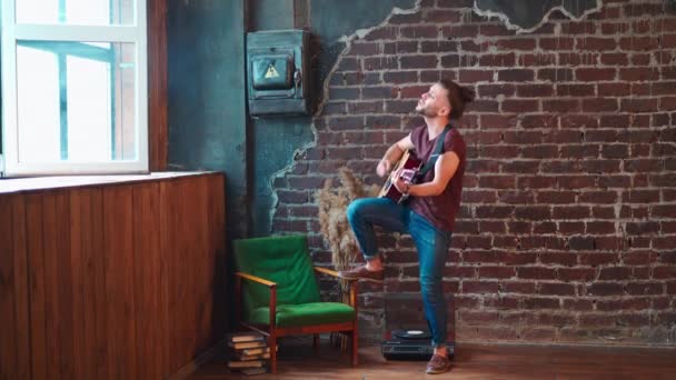 Чоловік з акустичною гітарою проти цегляної стіни грає музичні співочі пісні насолоджуватися життям Середня стрілянина — стокове відео