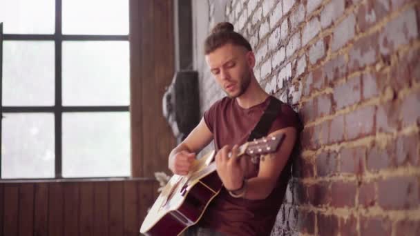 Man met akoestische gitaar leunend tegen bakstenen muur spelen muziek zingen liedjes genieten van het leven Medium schieten — Stockvideo
