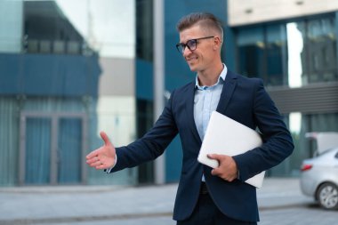 İş için. El sıkışmak için el sıkışan iş adamı, hoş geldin jesti, yetişkin beyaz erkek iş adamı, bilgisayarın kapalı tutulması, el sıkışmaya hazır ofis arka planı.