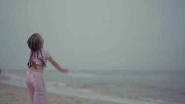 Küçük kızıyla birlikte deniz kıyısında uçurtma oynuyordu. Tek çocuklu mutlu beyaz bir aile deniz kıyısında yaz tatilinde eğleniyordu.