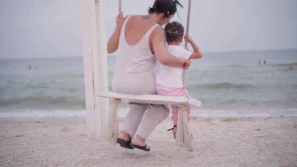Mor och barn svingar på stranden svinga med vacker havsutsikt familj med ett barn på semester — Stockvideo