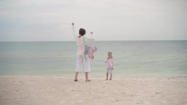 Küçük kızıyla birlikte deniz kıyısında uçurtma oynuyordu. Tek çocuklu mutlu beyaz bir aile deniz kıyısında yaz tatilinde eğleniyordu.