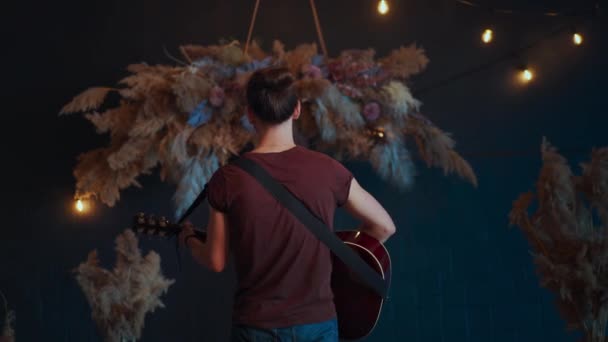 El músico masculino gira tocando la guitarra acústica. Guitarrista toca la guitarra clásica en el escenario en concierto — Vídeo de stock