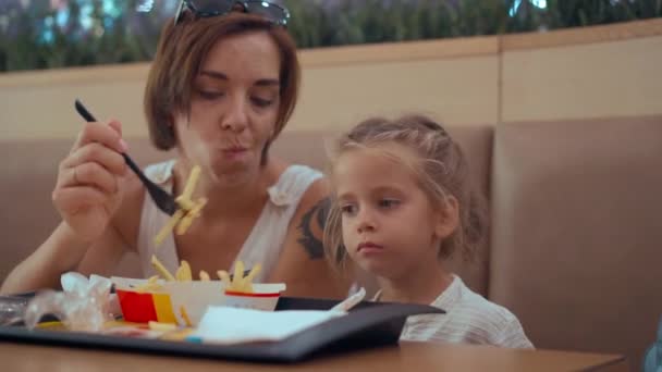 Kharkov, Oekraïne augustus 2021 Moeder en dochter eten gebakken friet in restaurant McDonalds voedselzone winkelcentrum — Stockvideo