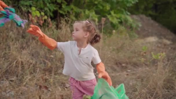 Niña ayuda a madre recoge basura plástica en la naturaleza para salvar el medio ambiente de la contaminación — Vídeo de stock