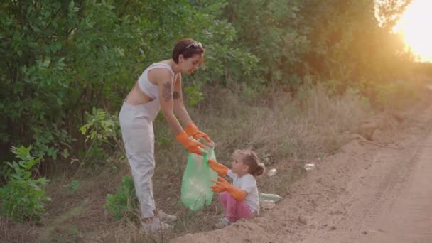 Meisje helpt moeder verzamelt plastic afval op de natuur om het milieu te redden van vervuiling — Stockvideo