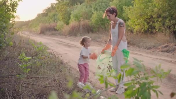 Malá dívka pomáhá matka sbírá plastové odpadky na přírodu zachránit životní prostředí před znečištěním — Stock video