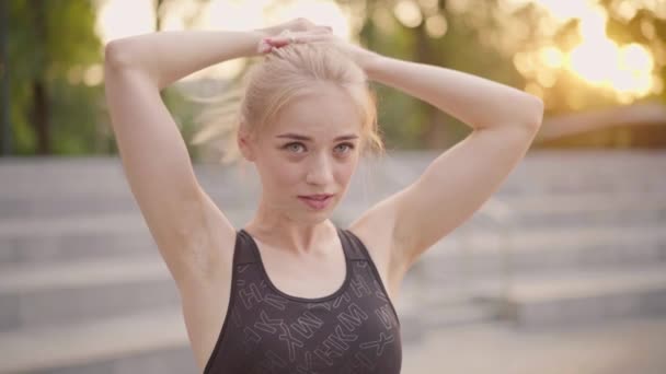体育与健身。白种人年轻女子领带马尾辫运动服站在户外夏季公园阳光背景 — 图库视频影像