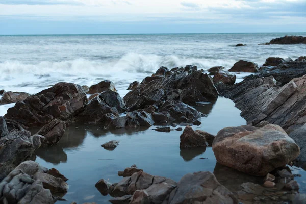 Резкий камень в море или океанская пена волна — стоковое фото