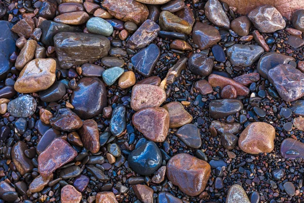 Textura de piedras de mar pequeñas y brillantes húmedas — Foto de Stock